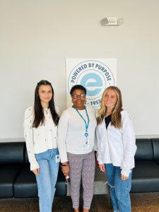High school summer interns, Lily and Phillips, with Eggleston Program Manager Elizabeth Johnson in from of Eggleston "Powered by Purpose" logo.